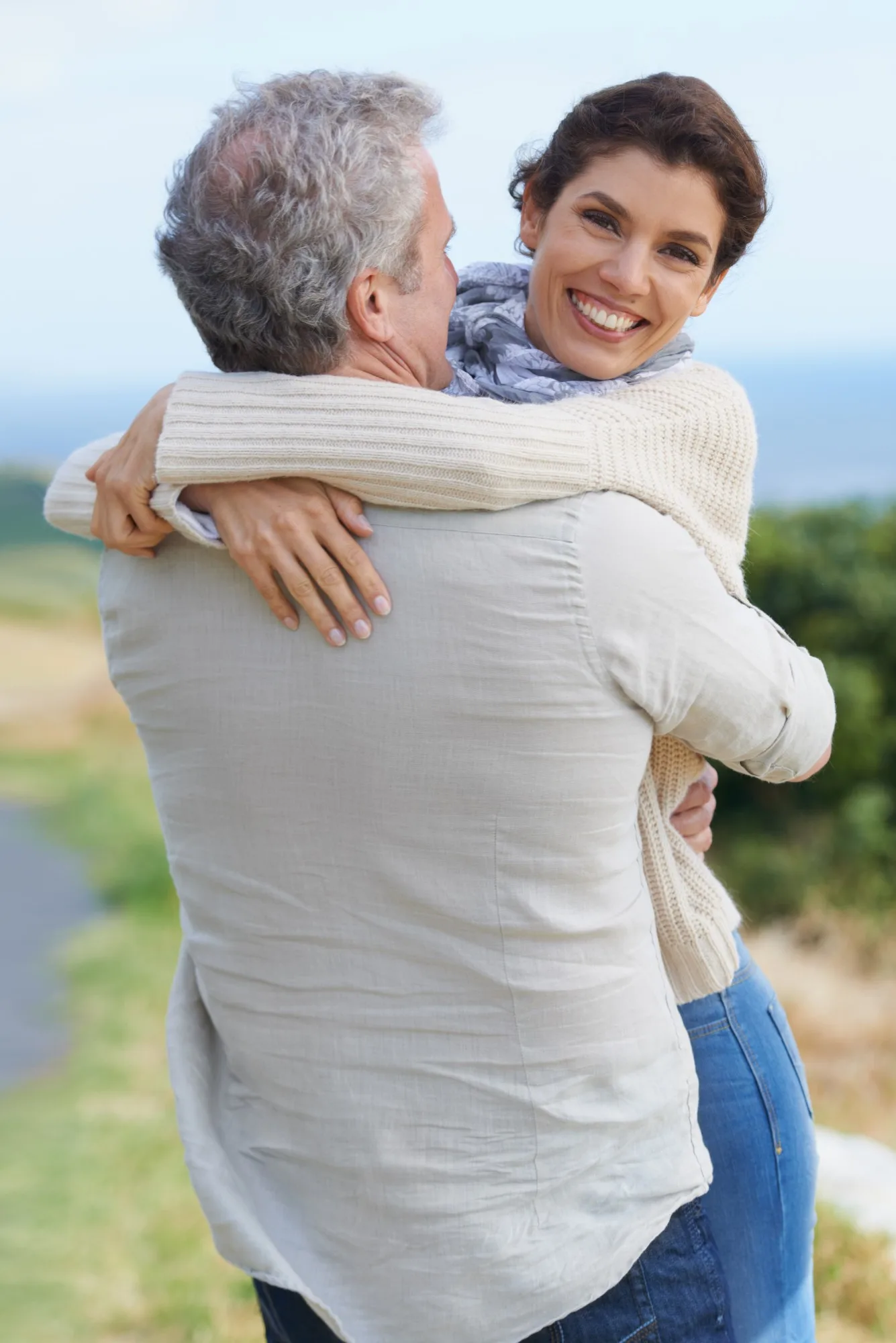 Smiling woman hugging her partner outdoors