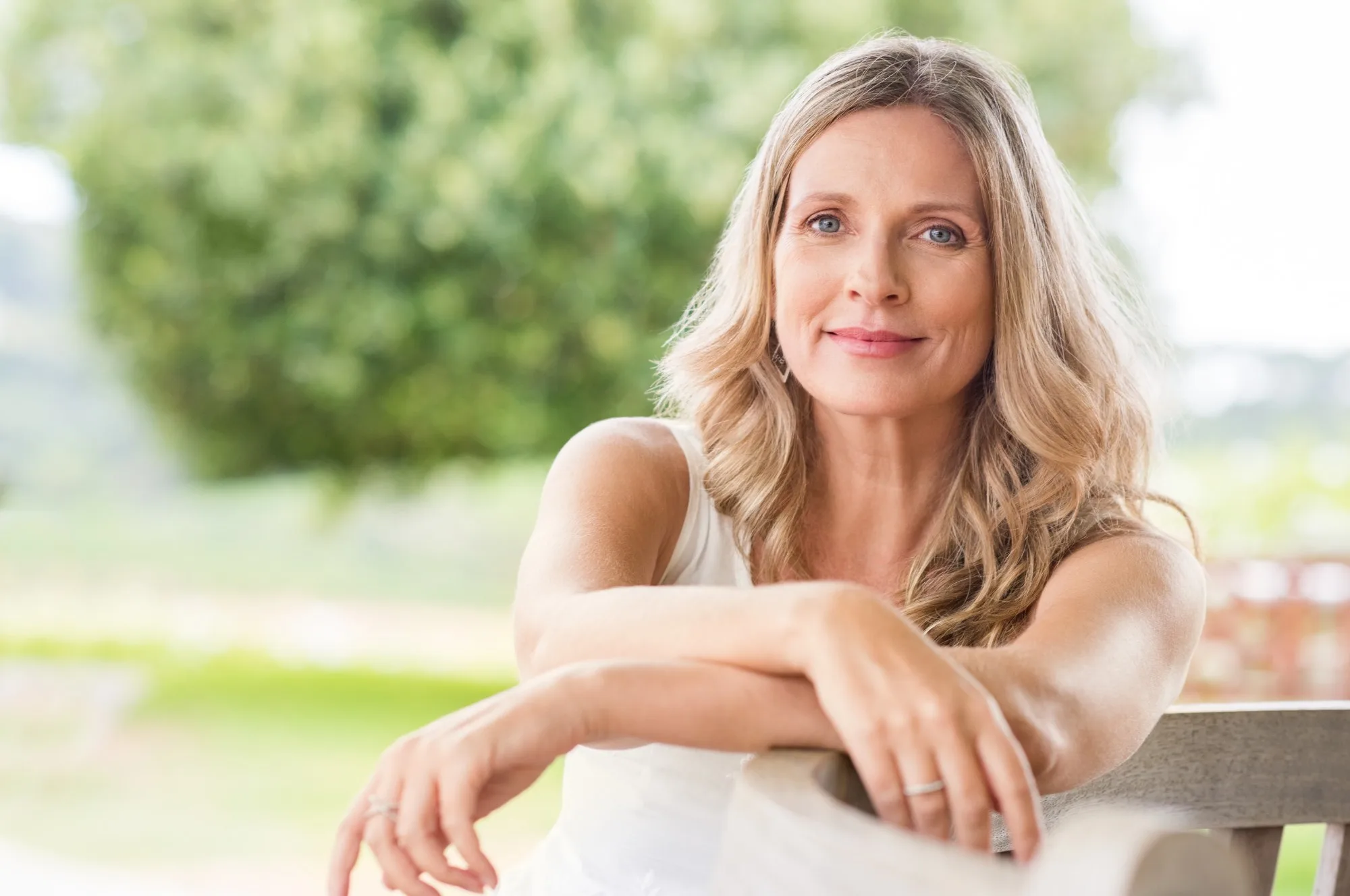 Smiling woman relaxing on a garden bench